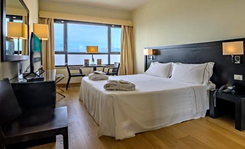 ein Hotelzimmer mit einem großen Bett und einem Schreibtisch in der Unterkunft Sardegna Hotel - Suites & Restaurant in Cagliari