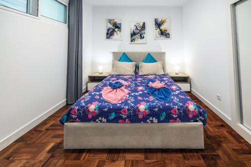 1 dormitorio con 1 cama con manta de flores en Sea Breeze I, en Caniço