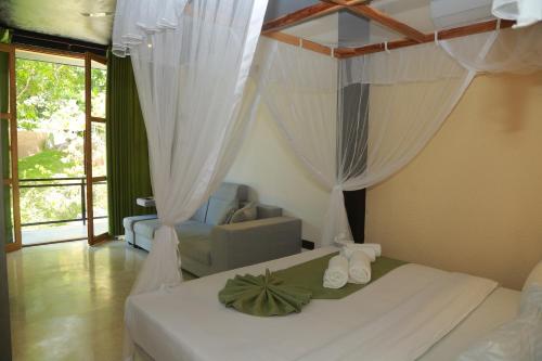 1 dormitorio con cama con cortinas y sofá en Mindara Villa, en Galle