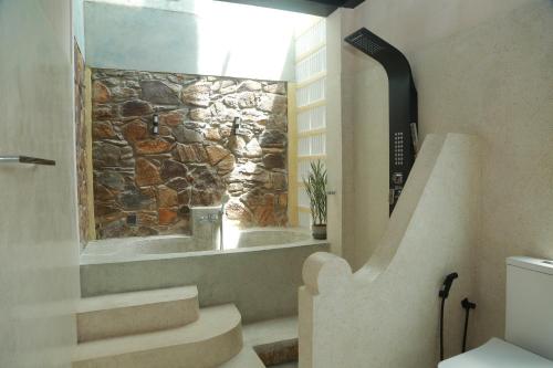 baño con escaleras y pared de piedra en Mindara Villa, en Galle