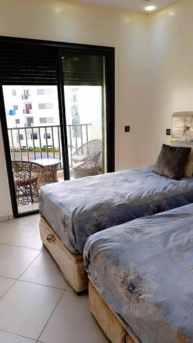 two beds in a room with a view of a balcony at Appartement Moderne avec Piscine in Bouznika