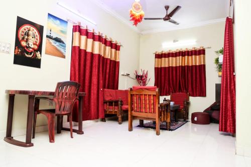 ein Wohnzimmer mit roten Vorhängen sowie einem Tisch und Stühlen in der Unterkunft SM Cottage in Mangaluru