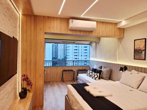 a hotel room with a bed and a balcony at Lindo e espaçoso studio com cama queen e cama solteiro in São Paulo