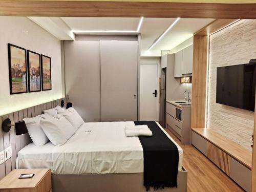a bedroom with a large bed and a flat screen tv at Lindo e espaçoso studio com cama queen e cama solteiro in São Paulo