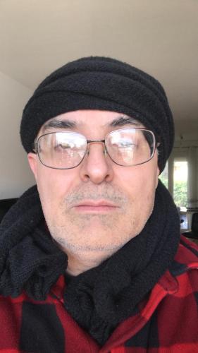 a man wearing glasses and a hat and a scarf at Auberge de Mourjou in Mourjou