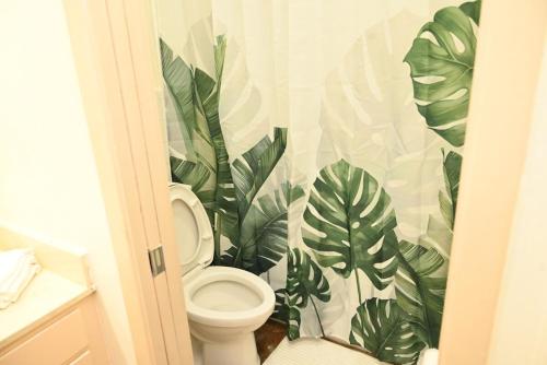 a bathroom with a toilet with a mural of leaves at Mid-City Rustic Retreat in Baton Rouge