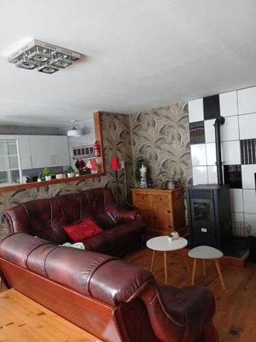 a living room with a leather couch and a table at Les 4 Portes in Le Mesnillard