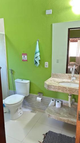 a green bathroom with a toilet and a sink at Pousada Cantinho da Mata in Paraty