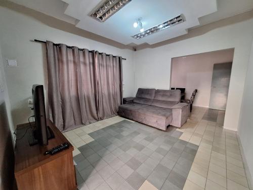 a living room with a couch and a tv at Casa 4 quartos no centro da cidade - 3 vagas de garagem in Campo Grande