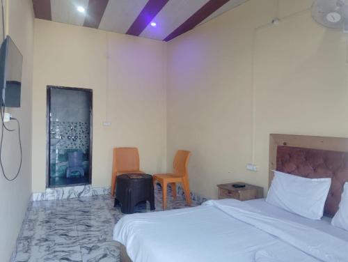 a bedroom with a bed and two chairs in it at Prithvi hotel and restaurant in Mussoorie