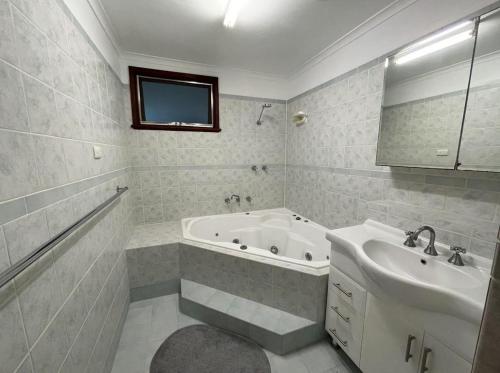 a white bathroom with a tub and a sink at The Newby in Lancelin