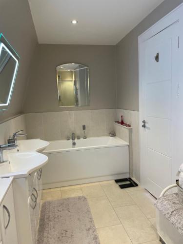 a white bathroom with a tub and a sink at Special Occasion, Stunning sea view balconied suite in Shoreham-by-Sea