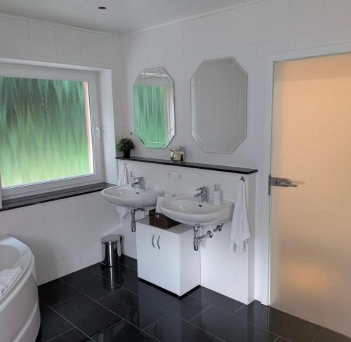 a white bathroom with two sinks and a toilet at Casa Viva in Niederdorla