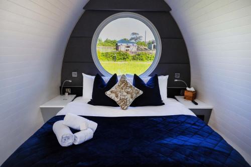 a bedroom with a large bed with a round window at Hidden Acres- Luxury Glamping Pod Sage in Malahide