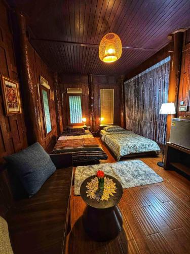 a living room with a couch and a table at Thai Classic House Rimtalay in Ban Rong Po