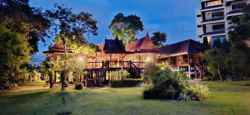 a large house with a yard in front of a building at Thai Classic House Rimtalay in Ban Rong Po