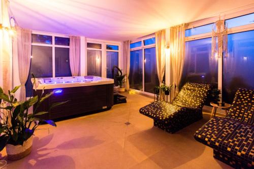Una habitación grande con bañera, sillas y ventanas. en Apartament Welle Lazurowy PREMIUM Grzybowo, en Grzybowo