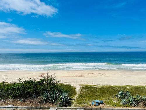 una playa con un banco azul y el océano en De frente ao MAR, en Saquarema