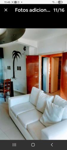 Ein weißes Sofa in einem Wohnzimmer mit einer Palme an der Wand in der Unterkunft Casa a metros de la playa in Mar del Plata