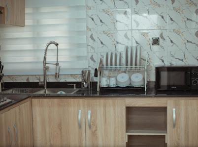 eine Küchentheke mit Spüle und Mikrowelle in der Unterkunft Royaltron apartment services in Ibadan