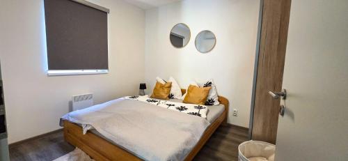 a bedroom with a bed with yellow pillows at Apartmánová chata u pláže Sečské přehrady in Hoješín