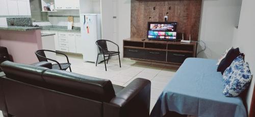 a living room with a couch and a table and a television at bairro Oliveira - casa 3 quartos com ar in Campo Grande
