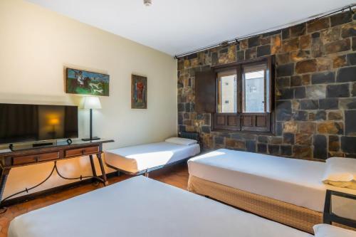 a room with two beds and a tv at Hotel Temple Ponferrada in Ponferrada