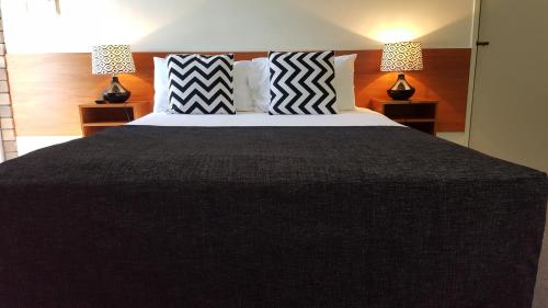 a bedroom with a large black bed with two lamps at Hampton Villa Motel in Rockhampton