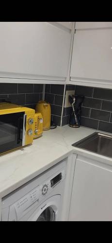 a kitchen with white cabinets and a washing machine at Morris lodge in Kew