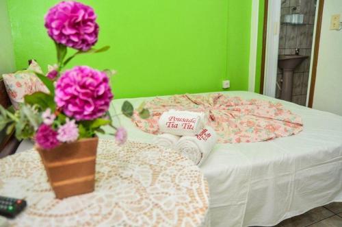 a bed with a vase of flowers on a table at Pousada Tia Tita in Cayru