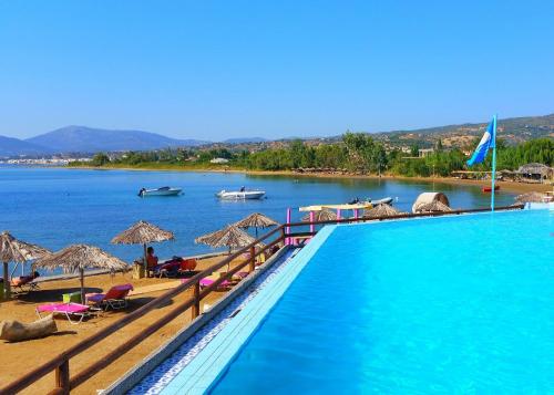 a swimming pool on a beach next to a body of water at Venus Beach Hotel in Nea Stira