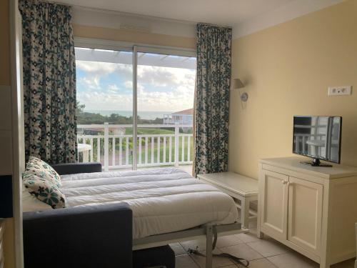 een slaapkamer met een bed en een raam met een balkon bij Les Sables-d'Olonne - Vue Mer, Terrasse, Wifi Fibre & Piscine, à 2 pas de l'Océan - E101 in Les Sables-dʼOlonne