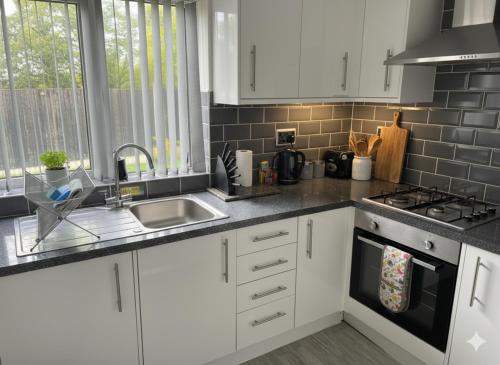 FlookburghにあるWillow Chalet near Cartmel & Lake Windermereの白いキャビネットとシンクのあるキッチン