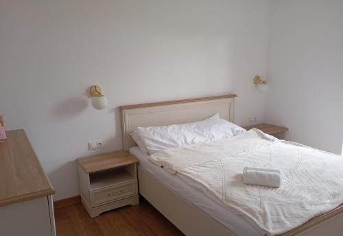 a bedroom with a white bed and a night stand at Górski Wypoczynek in Szczawnica