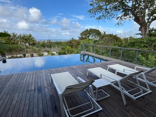 a deck with chairs and a swimming pool at Villa lagoon view Baie du cap bel ombre in Baie du Cap