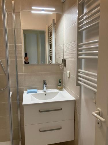 een badkamer met wastafel en douche met spiegel bij Les Sables-d'Olonne - Vue Mer, Terrasse, Wifi Fibre & Piscine, à 2 pas de l'Océan - E101 in Les Sables-dʼOlonne