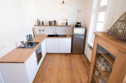 a small kitchen with white cabinets and a wooden floor at Modern design im klassischem Altbau in Weimar