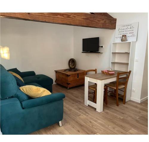 a living room with a blue couch and a table at Appartement calme in Sigogne