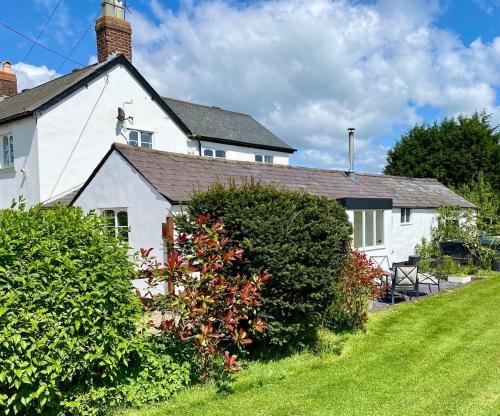 una casa blanca con un arbusto delante en Peewit Lodge, 