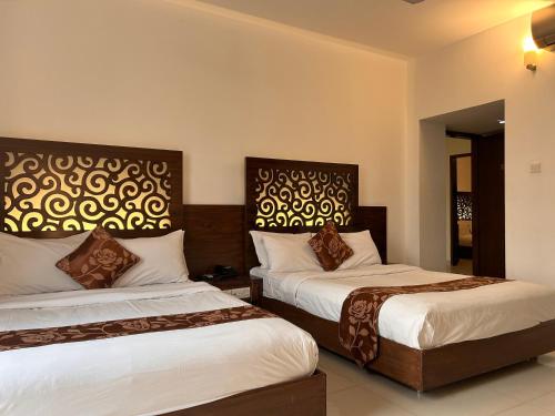 シレットにあるLa Vista Suites Sylhetのベッドルーム1室(ベッド2台、ヘッドボード付)