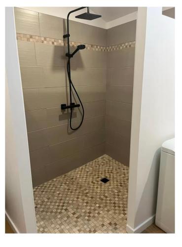 a shower with a shower head in a bathroom at Appartement calme in Sigogne