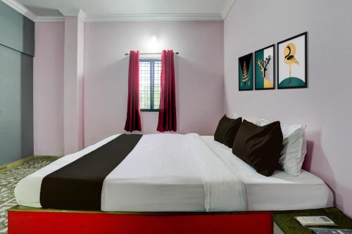 a bedroom with a large bed with red curtains at HOTEL O REEYH INN in Khāpri
