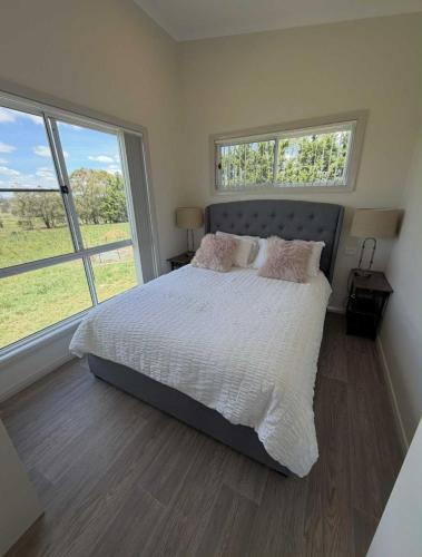 a bedroom with a large bed with two windows at Red Hill Cabin#2 - 2-bedroom in Walcha