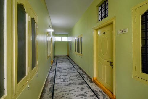 een lege gang met groene muren en een gele deur bij SPOT ON Harshitha Guest House in Pedda Ambarpet