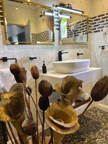 a bathroom with a sink and a mirror and flowers at Elilia in Beau Vallon