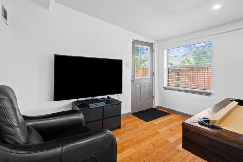 a living room with a black leather chair and a flat screen tv at Spacious 4BR w Fenced Yard in Round Rock