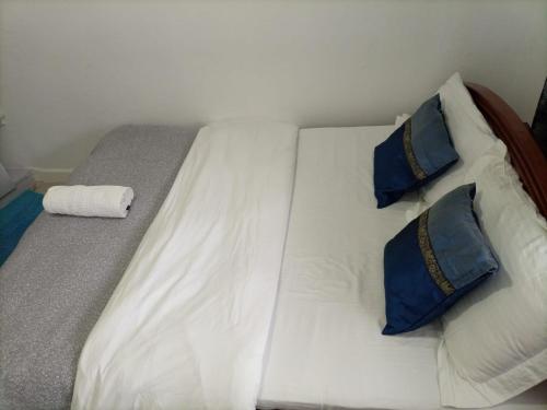 Una cama blanca con dos almohadas azules encima. en The Karen Haven, en Nairobi