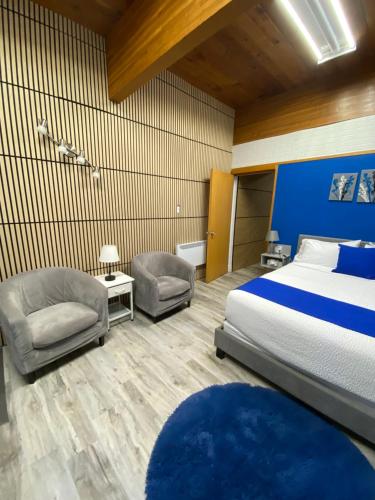 a hotel room with a bed and two chairs at Motel Magistral in St-Raphael-de-Bellechasse