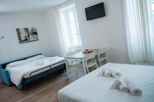 een slaapkamer met twee bedden, een tafel en een bureau bij City Gallery Apartments in Trieste