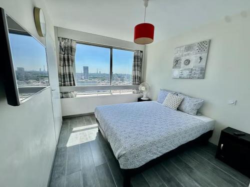 a bedroom with a bed and a large window at Apartment Paris La Défense Eiffel Tower Skyline in Puteaux